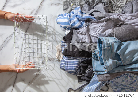 Woman hands putting stack of clean clothes for neatly tidying up and placing in steel wire wardrobe Woman hands putting stack of clean clothes for neatly tidying up and placing in steel wire wardrobe 71511764