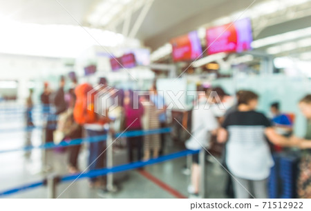 Blurred Airport Check-In Counters With Passengers And Crowd Control Barriers Blurred Airport Check-In Counters With Passengers And Crowd Control Barriers 71512922