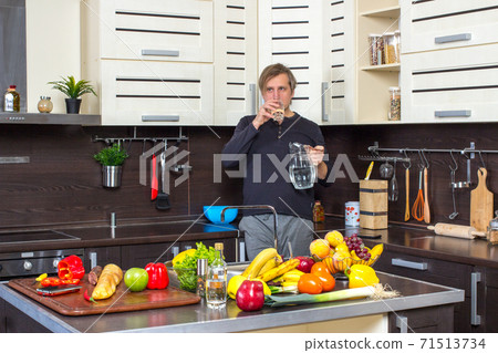 Man in kitchen with glass of water Man in kitchen with glass of water 71513734