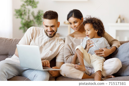 Diverse family using laptop on sofa together. Diverse family using laptop on sofa together. 71517381