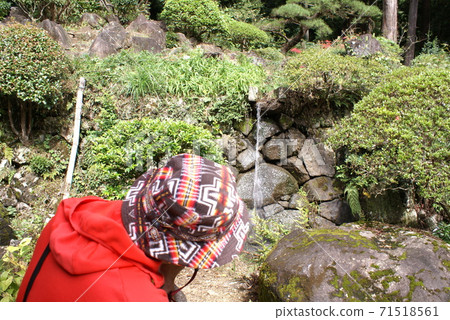 A person wearing a hat in a red hoodie staring at a small waterfall A person wearing a hat in a red hoodie staring at a small waterfall 71518561