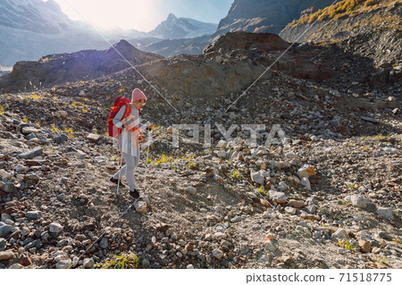Hiker woman with backpack in the mountains. Mountain with glacier and tourist Hiker woman with backpack in the mountains. Mountain with glacier and tourist 71518775