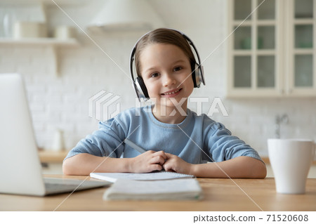 Head shot portrait smiling little girl wearing headphones studying online 71520608