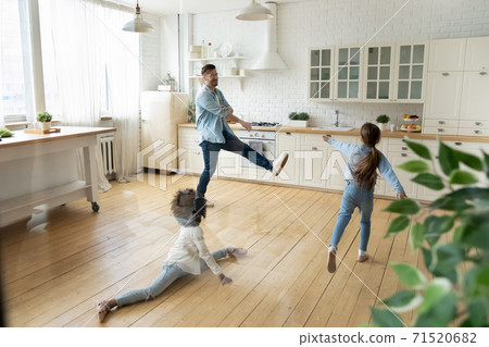 Happy young father having fun with diverse daughters in kitchen 71520682