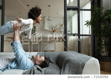 Caring Caucasian father carrying African American girl pretending flying Caring Caucasian father carrying African American girl pretending flying 71520703
