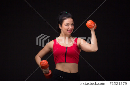 Brutal athletic woman pumping up muscules with dumbbells 71521279