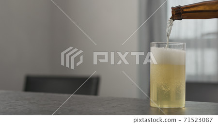 Slow motion pour kombucha into highball glass on concrete countertop with copy space 71523087