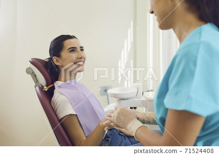 Dental specialist holding hand of happy woman sitting in chair at the dentist's office Dental specialist holding hand of happy woman sitting in chair at the dentist's office 71524408