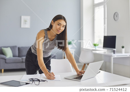 Young woman using laptop and writing in notebook planning her day, working remotely or studying 71524412
