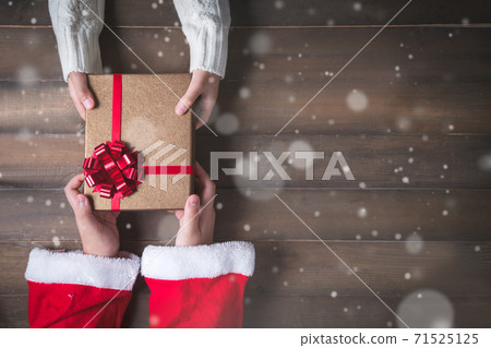 Little Santa Cross hands give gifts to children on Christmas Day. wood and snow background 71525125