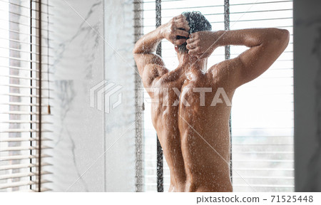 Handsome young man washing hair in bathroom, back view Handsome young man washing hair in bathroom, back view 71525448