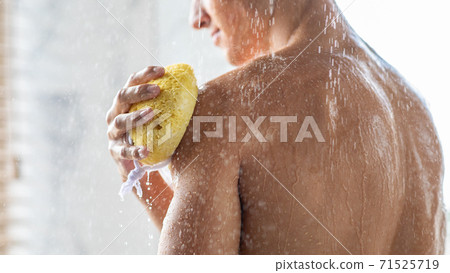 Young man washing his body with sponge Young man washing his body with sponge 71525719