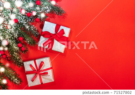 Xmas festive background with fir branches covered by snow, red berries, two DIY gift boxes tied with ribbons and bows on red. Christmas invitation or greeting card. Top view, copy space for text. Xmas festive background with fir branches covered by snow, red berries, two DIY gift boxes tied with ribbons and bows on red. Christmas invitation or greeting card. Top view, copy space for text. 71527802