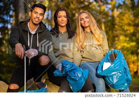 Multi-ethnic volunteers in environmental protection team sitting with garbage bags Multi-ethnic volunteers in environmental protection team sitting with garbage bags 71528024