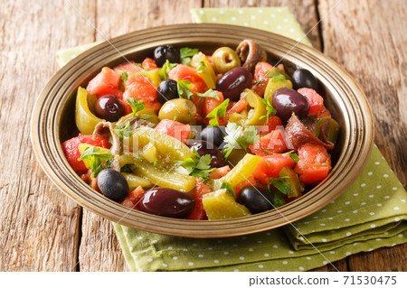 Tomato and green pepper salad with anchovies and olives close-up in a bowl. horizontal 71530475