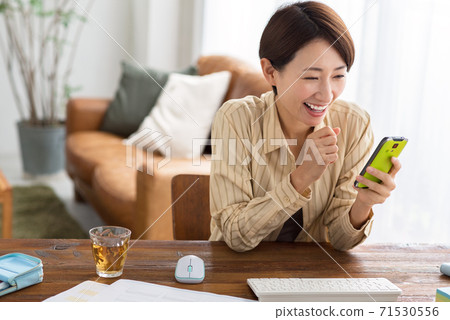 A middle-aged business woman checking her smartphone while teleworking at home 71530556