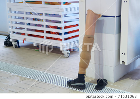 human leg prosthesis stands against the pool wall while its wearer swims human leg prosthesis stands against the pool wall while its wearer swims 71531068