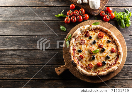 Homemade pizza with tomatoes mozzarella cheese olives and basil - top pof view Homemade pizza with tomatoes mozzarella cheese olives and basil - top pof view 71531739