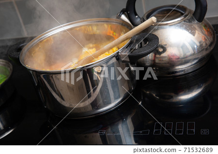 In the kitchen, colorful vegetables are cooked in a large nickel-plated pot. In the kitchen, colorful vegetables are cooked in a large nickel-plated pot. 71532689