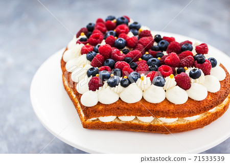 Delicious homemade heart shaped vanilla cake decorated with cream and fresh berries Delicious homemade heart shaped vanilla cake decorated with cream and fresh berries 71533539