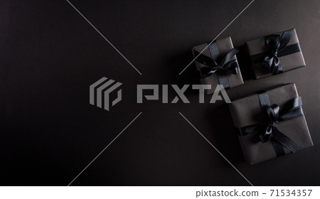 Top view of black Christmas gift boxes with black ribbon on black  background with copy space for text. Black Friday composition. 71534357