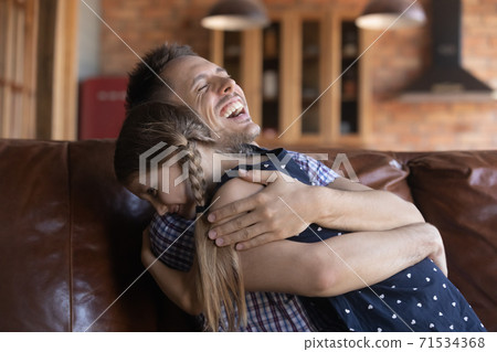 Joyful laughing daddy embracing small girl child with warmth Joyful laughing daddy embracing small girl child with warmth 71534368
