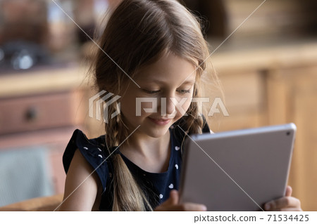Curious girl spending time at home alone using tablet pc Curious girl spending time at home alone using tablet pc 71534425
