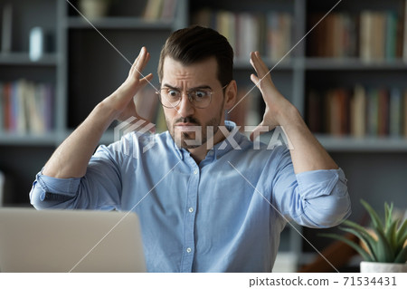 Employee looks at laptop feels angry having problems with device Employee looks at laptop feels angry having problems with device 71534431