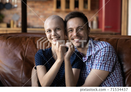 Loving husband hugging wife cancer patient on sofa at home Loving husband hugging wife cancer patient on sofa at home 71534437