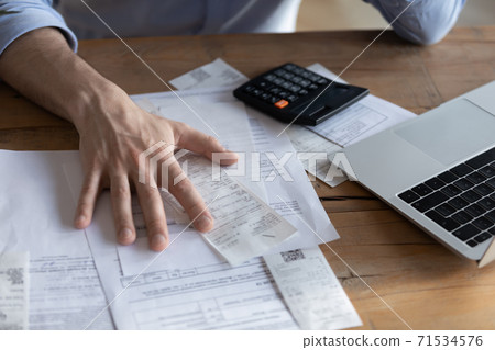 On desk lot of receipts calculator and laptop closeup view 71534576