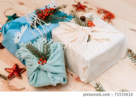 Zero waste gifts wrapped in fabric with spruce branch and berries on wooden background. 71535618
