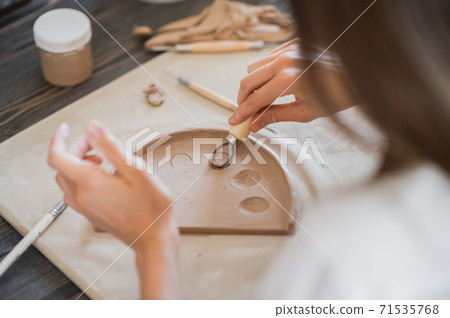 Close-up of a master potter, clay cutting special tool. Female artist cutting with a wooden loop tool Close-up of a master potter, clay cutting special tool. Female artist cutting with a wooden loop tool 71535768