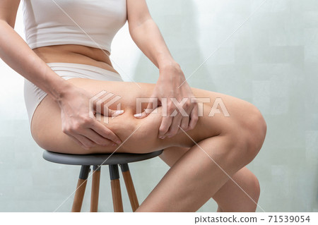 Young women shows holding and pushing the skin of the legs cellulite. Young women shows holding and pushing the skin of the legs cellulite. 71539054