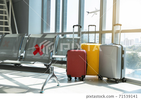 Traveling luggage in airport terminal and passenger plane flying over sky. 71539141