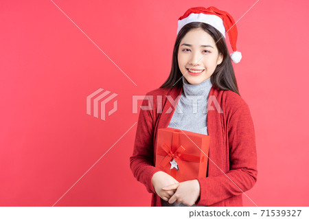 Beautiful Asian woman holding red gift box on red background 71539327