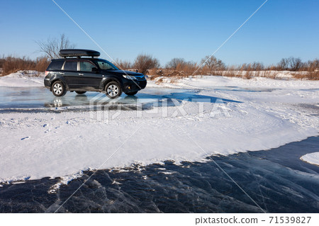 Subaru Forester with rooftop box at frozen lake ice. Subaru Forester with rooftop box at frozen lake ice. 71539827