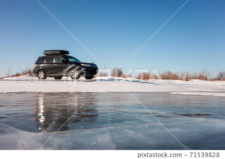 Subaru Forester with rooftop box at frozen lake ice. 71539828