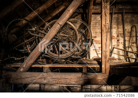 A rusty old vintage bikes in a barn with old farm machinery 71542086