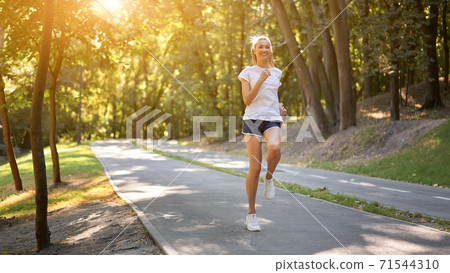 Woman running asphalt road summer park Woman running asphalt road summer park 71544310