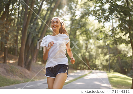 Woman running asphalt road summer park Woman running asphalt road summer park 71544311