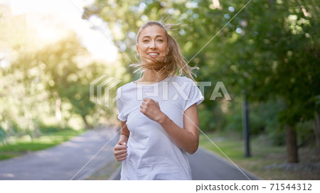 Woman running asphalt road summer park Woman running asphalt road summer park 71544312