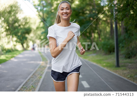 Woman running asphalt road summer park Woman running asphalt road summer park 71544313