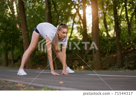 Woman runner stretching legs before exercising summer park  morning 71544317