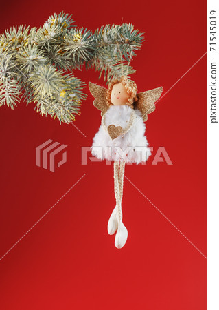 Handmade christmas angel toy on a Christmas tree on a red background. 71545019