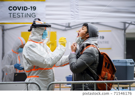 Young man in covid-19 testing center outdoors on street, coronavirus and taking swab concept. 71546176