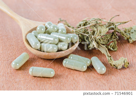 Herb medical capsules in wooden spoon with dry leaves herb. Herb medical capsules in wooden spoon with dry leaves herb. 71546901