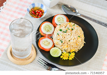 fried rice and vegetable in black dish. 71546957