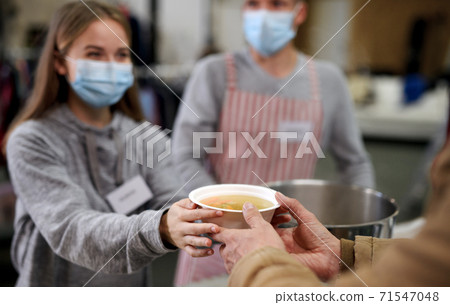 Volunteers serving hot soup for homeless in community charity donation center, coronavirus concept. 71547048