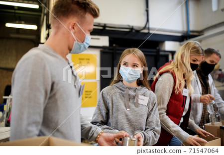 Group of volunteers in community charity donation center, food bank and coronavirus concept. 71547064