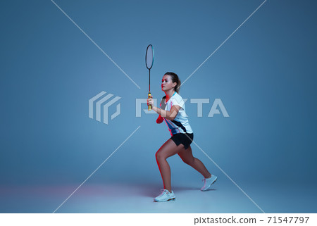 Beautiful handicap woman practicing in badminton isolated on blue background in neon light Beautiful handicap woman practicing in badminton isolated on blue background in neon light 71547797